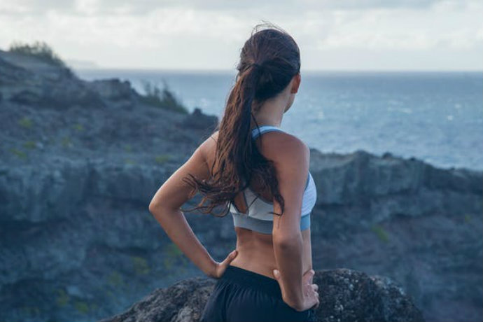 Women in sports bra looking out to sea